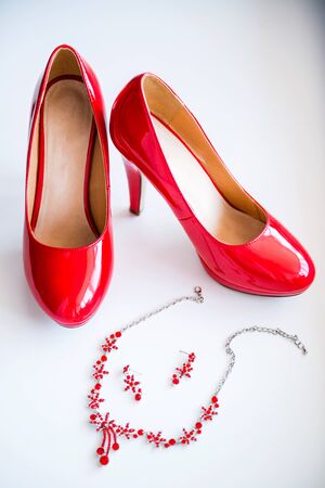 Women's red wedding shoes and earrings with necklaces. White background.の写真素材
