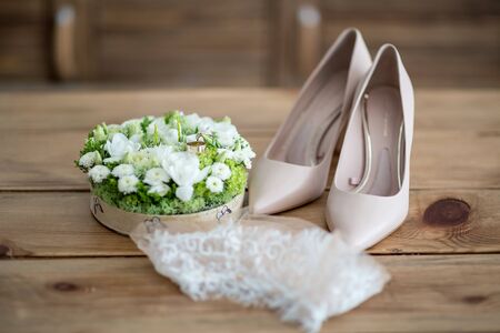 Wedding rings, wedding flowers, shoes, stocking, on a wooden tableの写真素材