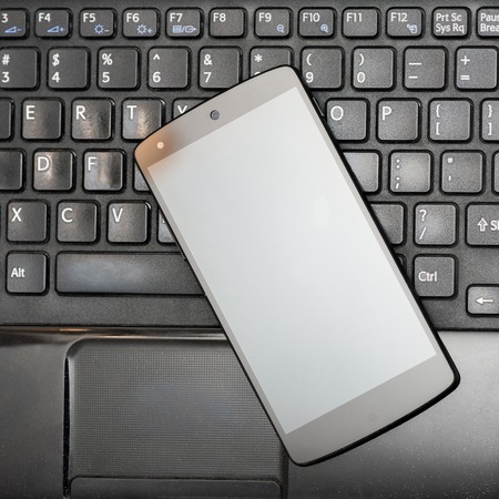 Close look of smartphone on black laptop keyboardの写真素材