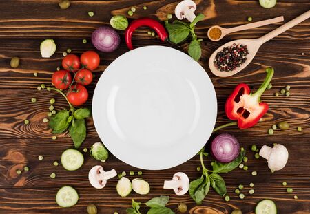 On a wooden table lies a plate, surrounded by Italian products and spicesの写真素材