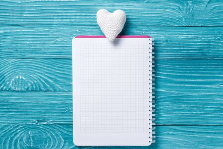 Blank notepad for copy space and vintage handmaded valentines day toy white heart over blue wooden...