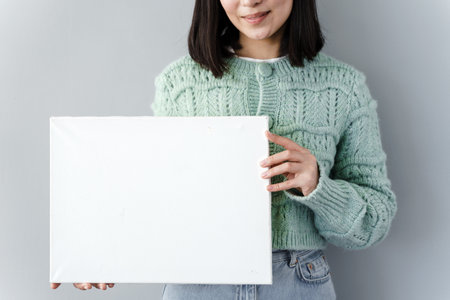 Girl with a sheet of paper in hand. Close view, girl on a background of gray stent, copy space.