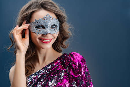 Portrait of a young woman in a carnival mask and dress with sequins smiling close-upの写真素材