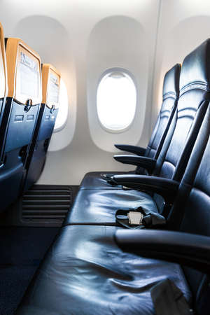 Plane interior - cabin with modern leather chair for passenger of airplane. Aircraft seats and window. - Vertical imageの写真素材