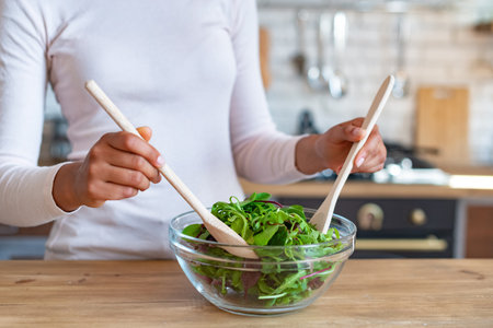 Closeup female hands during cooking a healthy food, stirs with spoons a saladの写真素材