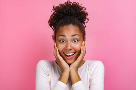 Closeup portrait of a pretty mulatto girl over pink background with amazed emotion on face - Imageの写真素材