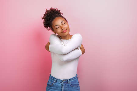 Cute mulatto woman hugging herself feeling a comfort, calmness and love. Concept gesture - Imageの写真素材