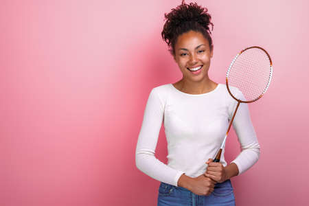 Sporty mulatto girl standing with badminton racket in the studio looking at the cameraの写真素材