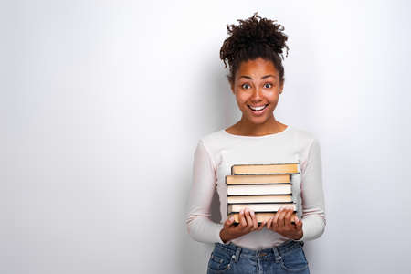 Portrait of an excited young girl holding books over white background. Back to schoolの写真素材