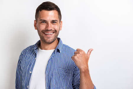 Handsome happy man pointing by his big finger backward and looking at the camera.- Image