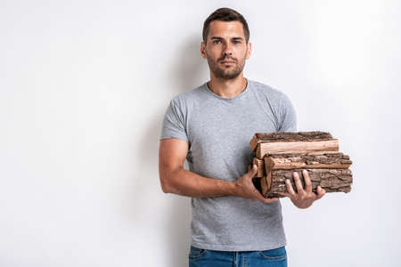 Handsome man stands over white studio background and holding a firewood.- Imageの写真素材