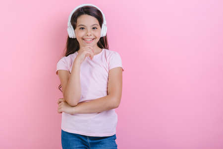 Portrait of happy little girl in earphones listening to music and looking at the camera- Imageの写真素材