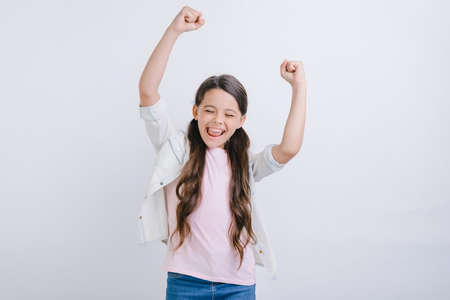Excited girl raised hands in success gesture in studio. Concept gesture - Imageの写真素材
