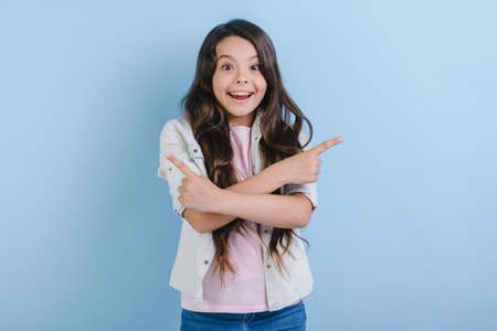 Excited young girl pointing her index finger right and left with crossing hands. Concept gesture - Imageの写真素材