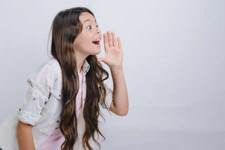 Studio profile portrait of screaming little girl with hand next her face.- Imageの写真素材