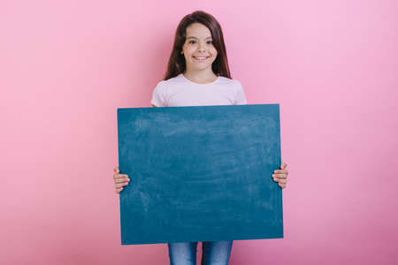Schoolgirl stands holding a blackboard in her hands . - Imageの写真素材