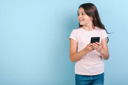 Girl holding mobile phone with happy looking sideaway. - Imageの写真素材