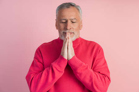 Man with closed eyes meditates on a pink background. The concept of spirituality, faith.の写真素材