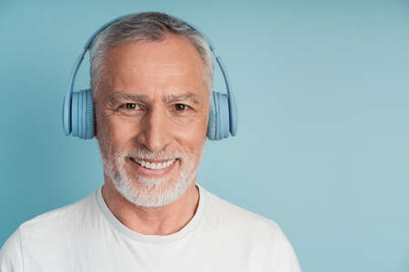 Close-up view, positive man in headphones smiling on blue background. Isolated on blank wall background.の写真素材