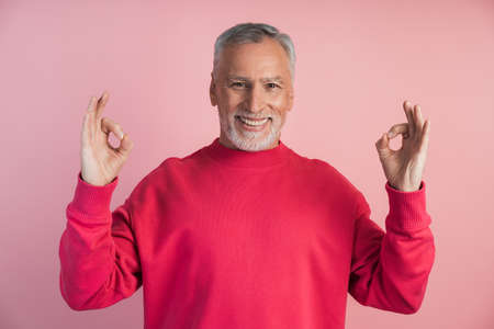 Smiling man meditating on a pink background. The concept of spirituality, faith.の写真素材