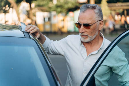 Businessman senior man gets into his car after a hard work dayの写真素材