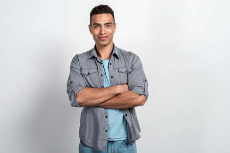 Studio shoot of a handsome man against  the white wall, folded his handsの写真素材