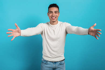 Portrait of a happy friendly young man in white shirt makes hugging gesture - Imageの写真素材