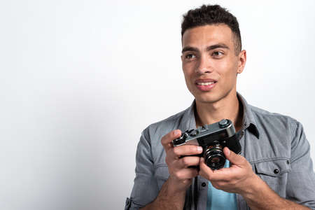 Portrait of happy mulatto man holding vintage photocamera. Touristic concept image. - Copy spaceの写真素材