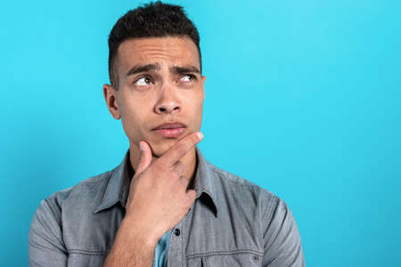 Modern man on blue background thinking about somethingの写真素材