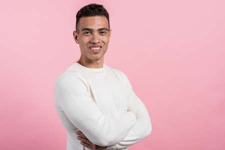 Closeup half-turn portrait of happy  mulatto man posing in the studio against a pink background.- Imageの写真素材