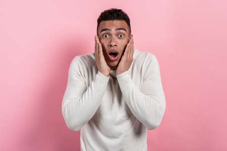 Surprised pretty man with open mouth posing in the studio against a pink background looking at the camera.- Imageの写真素材