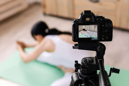 Attractive young woman practicing yoga and shooting videoの写真素材
