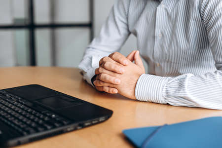 Businessman clasped hands on desk, working on computerの写真素材