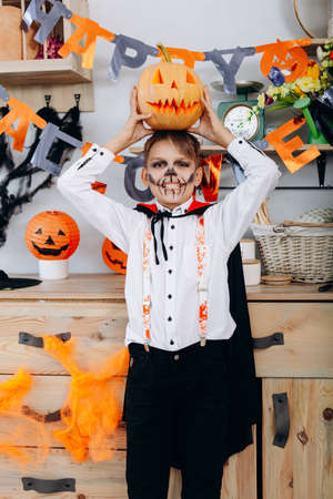 Boy standing  in masquerade  dress holding a pumpkin on his head - Halloween conceptの写真素材