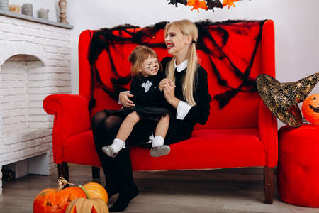 Woman and little girl have a funny time on red sofa. Emotion and Halloween conceptの写真素材