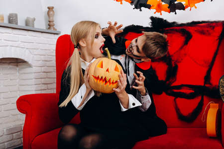 Mother and son have a funny time on red sofa. Boy scary woman.  Halloween conceptの写真素材