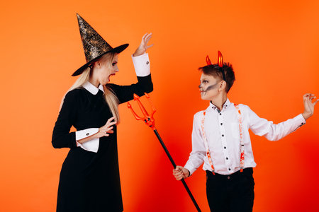 Mother and sun in Devil masquerade makeup scare each other. Halloween concept