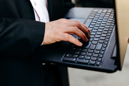 Cropping image of senior businessman holding laptop in his hand and typing closeup.- Imageの写真素材