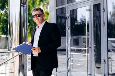 Portrait of happy senior businessman in sunglasses holding a document. - Imageの写真素材