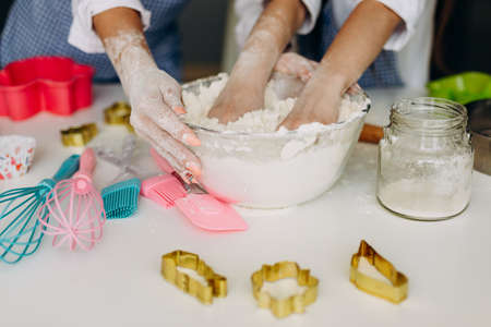 Closeup female and kids hands in a plate knead the doughの写真素材