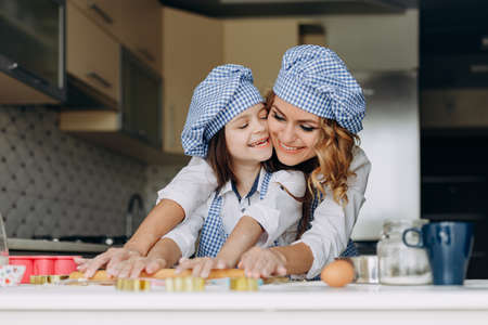 Little girl and mother  roll out the dough with a rolling pin together .- Imageの写真素材