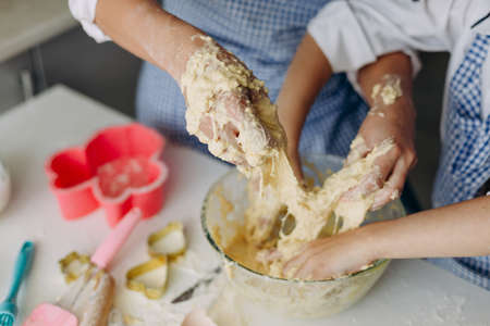 Closeup daughter and mother are stir the dough together and dirty they arms- Imageの写真素材