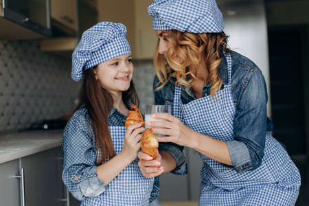 Portrait of mother and daughter holding croissants and milk .Family conceptの写真素材