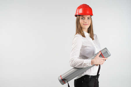 Smiling woman  stands  in orange helmet holds tube. - Place for textの写真素材