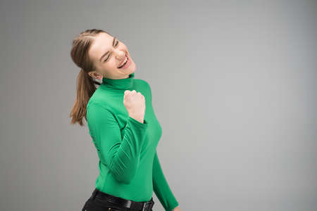 Happy young woman closed eyes with cleanch fist up and smiling with opened mouth .- Imageの写真素材