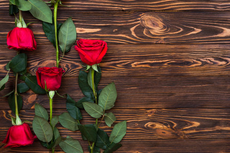 On a wooden surface are red rosesの写真素材