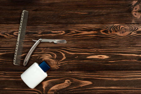 Comb, metal shaving razor, cream jar on the wooden backgroundの写真素材