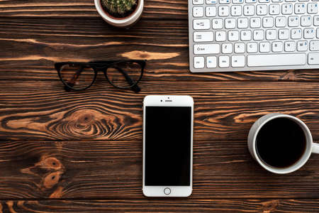 Top view office desk with a cup of coffee and smartphone and glassesの写真素材