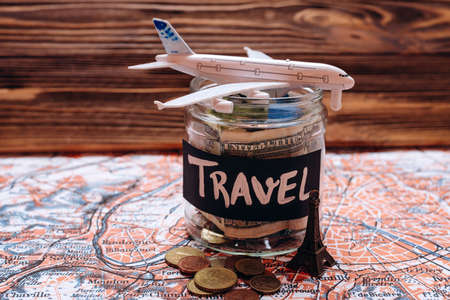 Collecting money for travel, money savings in a glass jar with world map. High quality photoの写真素材