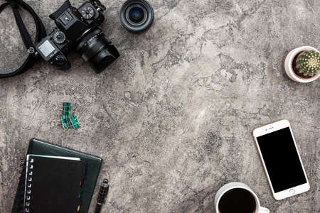 Top view a plaster background with a photocamera, smartphone and stationeryの写真素材